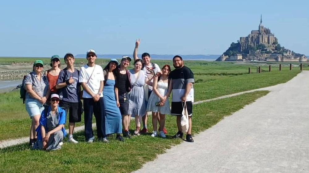 Le groupe pose sur le chemin menant au Mont-Saint-Michel sous un grand ciel bleu