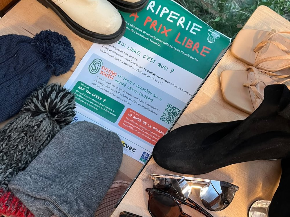 Vêtements et accessoires de seconde main à côté de l'affiche de la friperie à prix libre